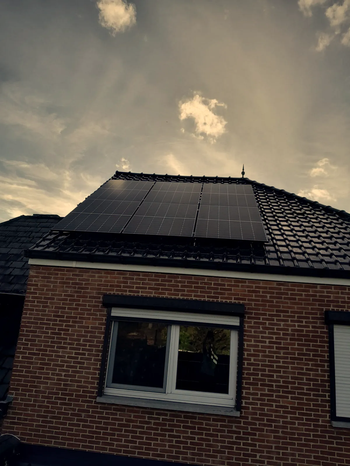 Zonnepanelen op het zwarte pannendak van een bakstenen woning